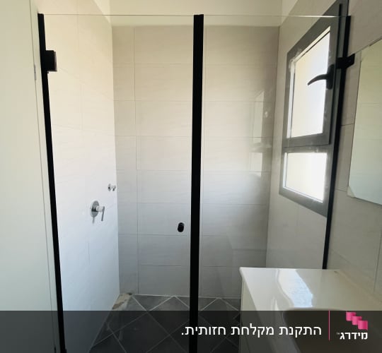 מקלחון חזית זכוכית מותקן בנישה עם פרופילים וצירים בצבע שחור